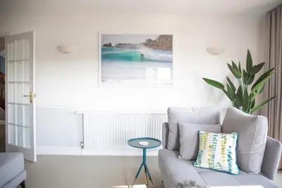 a white living room with a couch and a table at Newquay Tamarisk Lodge on the Gannel in Newquay