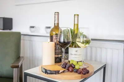 a table with two bottles of wine and grapes at Newquay Tamarisk Lodge on the Gannel in Newquay