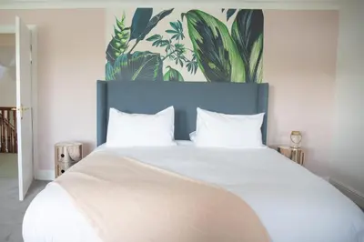 a bedroom with a large white bed with a blue headboard at Newquay Tamarisk Lodge on the Gannel in Newquay