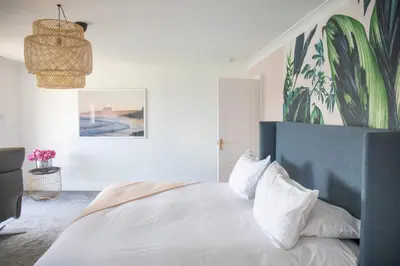 a bedroom with a white bed with a blue headboard at Newquay Tamarisk Lodge on the Gannel in Newquay