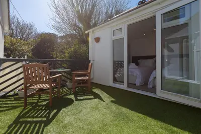 a screened in porch with a bed and a chair at Glenside House in Carbis Bay