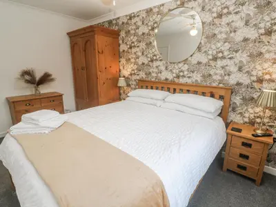 a bedroom with a large bed and a mirror at Chellowdene Cottage in Falmouth