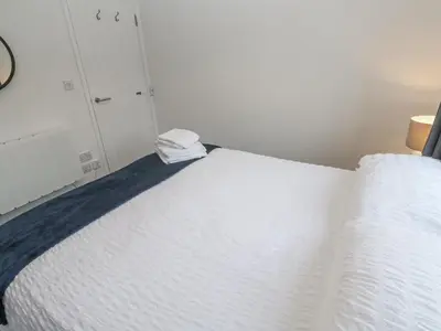 a bedroom with a bed with white sheets at Chellowdene Cottage in Falmouth