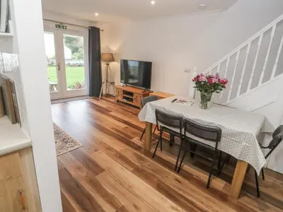 a dining room with a table and a television at Chellowdene Cottage in Falmouth