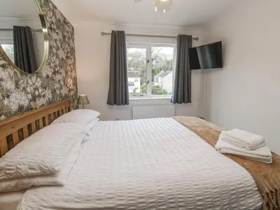 a bedroom with a large bed and a mirror at Chellowdene Cottage in Falmouth