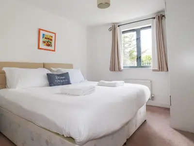 a large white bed in a room with a window at Spinnaker in St Austell
