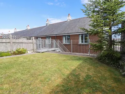 a red house with a fence and a yard at Spinnaker in St Austell