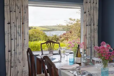 a dining room with a table and a large window at High Meadows in Saint Mawes