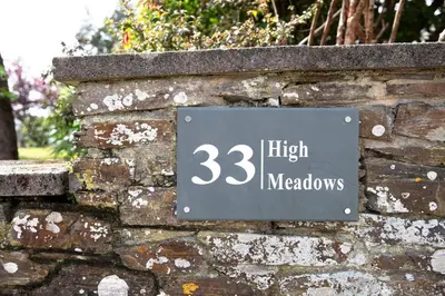 a sign on the side of a brick wall at High Meadows in Saint Mawes