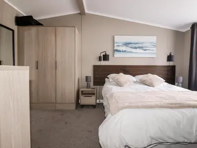 a bedroom with a large white bed and a night stand at 63 The Maples in St Austell