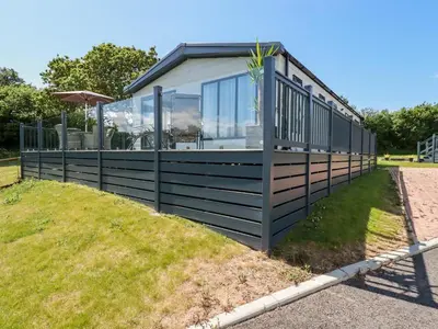 a house on a grassy hill with a building at 63 The Maples in St Austell