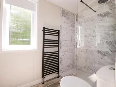 a bathroom with a marble shower with a toilet at 63 The Maples in St Austell