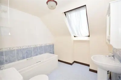 a white bathroom with a sink and a tub and a toilet at Direct Beach Access! Top Floor Apartment Perranporth in Perranporth