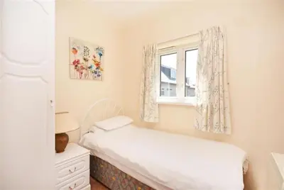 a small bedroom with a bed and a window at Direct Beach Access! Top Floor Apartment Perranporth in Perranporth