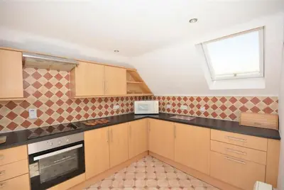 a kitchen with wooden cabinets and a window at Direct Beach Access! Top Floor Apartment Perranporth in Perranporth
