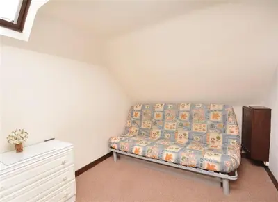 a room with a bed and a dresser in a room at Direct Beach Access! Top Floor Apartment Perranporth in Perranporth