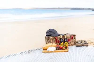 a picnic basket on the beach with shoes and sandals at NEW! Stunning 2 Bed Beach Front Penthouse Apartment - Topaz, Compass Point in Carbis Bay