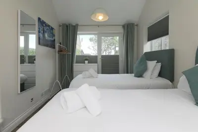 a bedroom with two beds and a mirror at Spernenwyn in St Ives