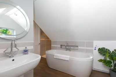 a bathroom with a sink and a tub and a mirror at Spernenwyn in St Ives