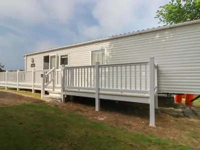 a white mobile home with a porch and a fence at Chez Nous in Newquay