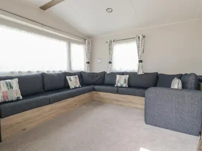 a living room with a blue couch and two windows at Chez Nous in Newquay