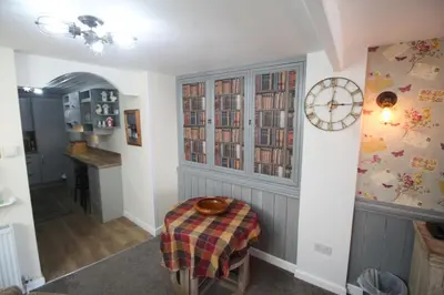 a room with a table and a clock on a wall at Briar Cottage in Looe