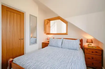 a bedroom with a bed and a window and a wooden door at Sunset View, near Gwithian & St.Ives Bay in Gwithian