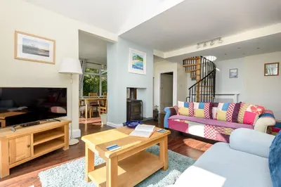 a living room with a couch and a table at Beach Front House with Stunning Sea Views and Free Use of a Local Indoor Pool in Talland