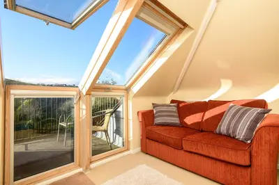 a living room with a red couch in front of a window at Beach Front House with Stunning Sea Views and Free Use of a Local Indoor Pool in Talland