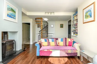 a living room with a couch and a fireplace at Beach Front House with Stunning Sea Views and Free Use of a Local Indoor Pool in Talland