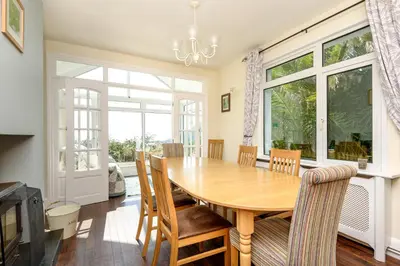 a dining room with a wooden table and chairs at Beach Front House with Stunning Sea Views and Free Use of a Local Indoor Pool in Talland