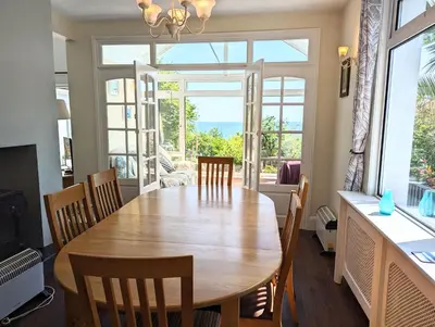 a dining room with a large wooden table and chairs at Beach Front House with Stunning Sea Views and Free Use of a Local Indoor Pool in Talland