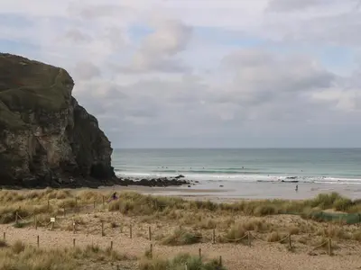 a beach with people in the water and a cliff at 16 Seaspray in Truro