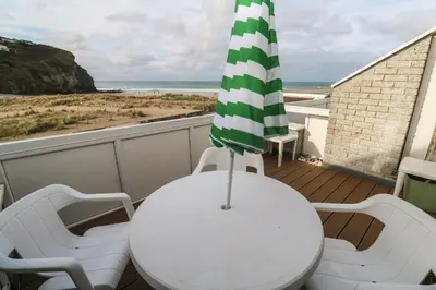 a balcony with a table and two chairs and an umbrella at 16 Seaspray in Truro