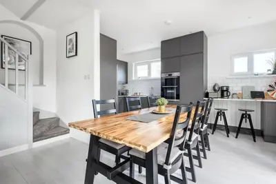 a kitchen and dining room with a wooden table and chairs at Spacious, Modern Home, Central Newquay w/ parking in Newquay