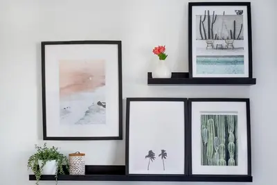 three framed pictures on a white wall with plants at Spacious, Modern Home, Central Newquay w/ parking in Newquay