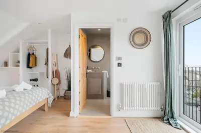 a white bedroom with a bed and a bathroom at Stylish & Modern Home, Central Newquay w/parking in Newquay