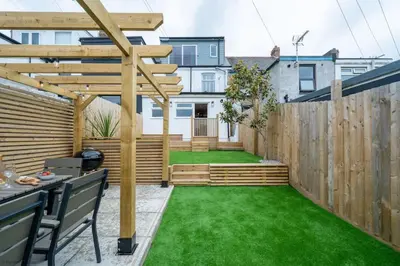 a backyard with a wooden fence and green grass at Stylish & Modern Home, Central Newquay w/parking in Newquay