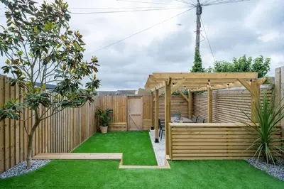 a garden with a wooden fence and green grass at Stylish & Modern Home, Central Newquay w/parking in Newquay
