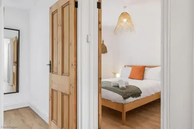 a bedroom with a bed with white sheets and orange pillows at Stylish & Modern Home, Central Newquay w/parking in Newquay