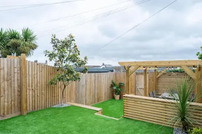 a backyard with a wooden fence and green grass at Stylish & Modern Home, Central Newquay w/parking in Newquay