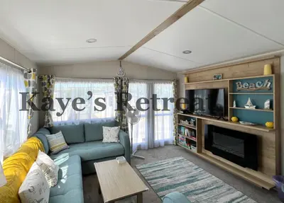 a living room with a blue couch and a tv at Kayes Retreat Three bed caravan Newquay Bay Resort Quieter area of park in Newquay