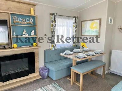 a living room with a table and a blue chair at Kayes Retreat Three bed caravan Newquay Bay Resort Quieter area of park in Newquay