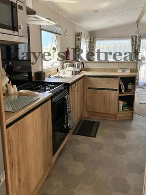 a kitchen with wooden cabinets and a stove top oven at Kayes Retreat Three bed caravan Newquay Bay Resort Quieter area of park in Newquay