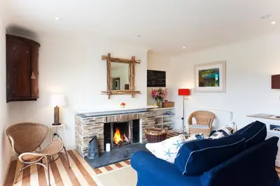 a living room with a blue couch and a fireplace at Nearwater in Saint Mawes