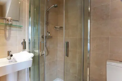 a shower with a glass door next to a sink at Nearwater in Saint Mawes