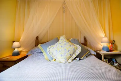 a bedroom with a bed with two tables and two lamps at Polraen Country House Hotel in Looe