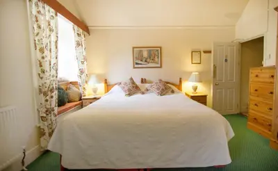 a bedroom with a white bed and a window at Polraen Country House Hotel in Looe