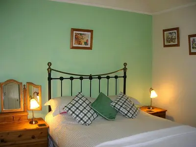 a bedroom with a bed with pillows and two lamps at Polraen Country House Hotel in Looe