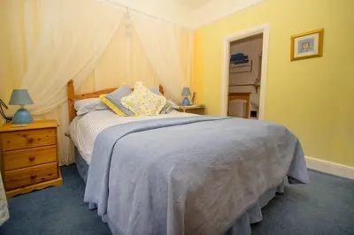 a bedroom with a bed and a dresser and a mirror at Polraen Country House Hotel in Looe